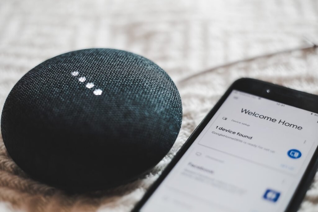 Smart speaker beside a phone showing a home setup screen